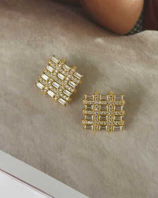 Gold square earrings on a neutral background